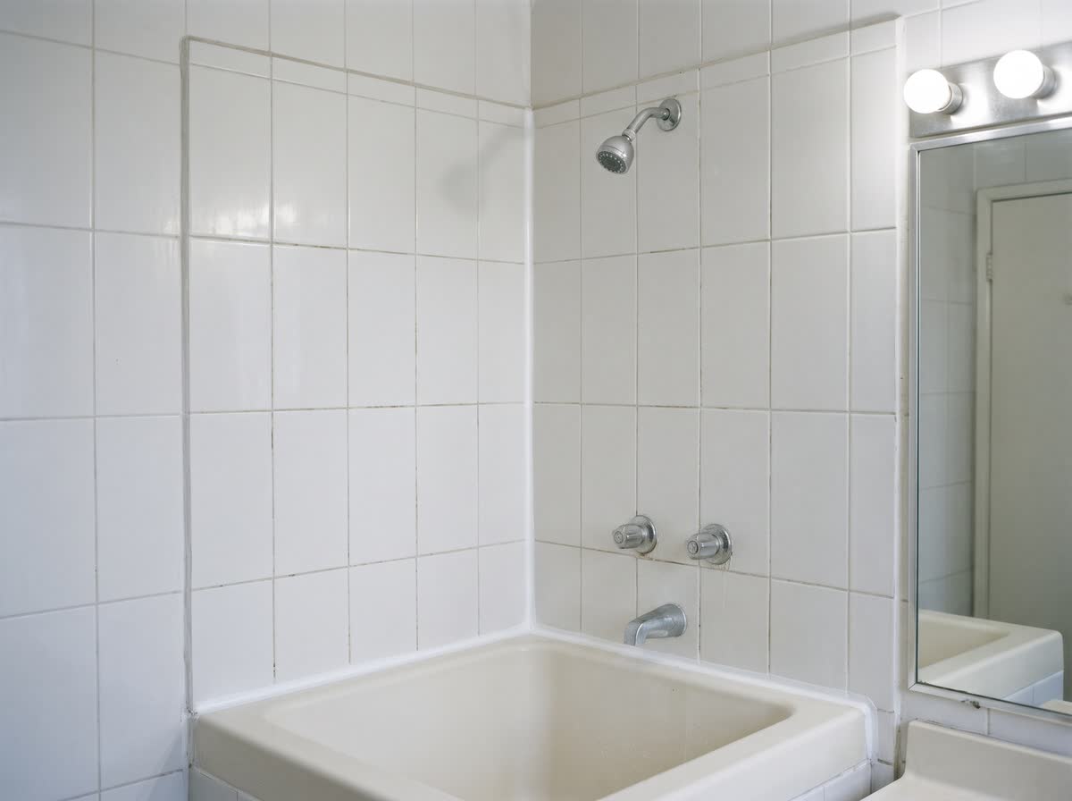 Baño de la habitación 204 después de la orden: silicón nuevo con antihongos, iluminación completa y junta limpia